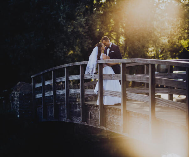 para młoda stojąca na moście podczas zachodu słońca